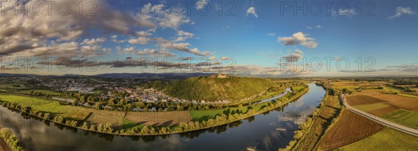 A picturesque landscape shows the Danube meandering through the green surroundings. Hills and clouds form an impressive backdrop at sunset. The pilgrimage church of the Assumption of the Virgin Mary on Bogenberg can be seen in the background. Bogen, Lower Bavaria