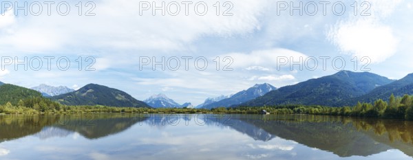 Panoramic lake reflects the surrounding mountains and the slightly cloudy sky, Admont, Styria, Austria