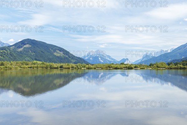 Panoramic lake reflects the surrounding mountains and the slightly cloudy sky, Admont, Styria, Austria
