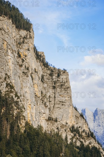 Steep rock face with forest at its feet, rising into blue sky, Admont, Styria, Austria