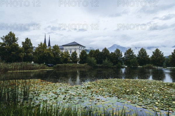Admont Abbey behind a pond surrounded by trees, Admont, Styria, Austria