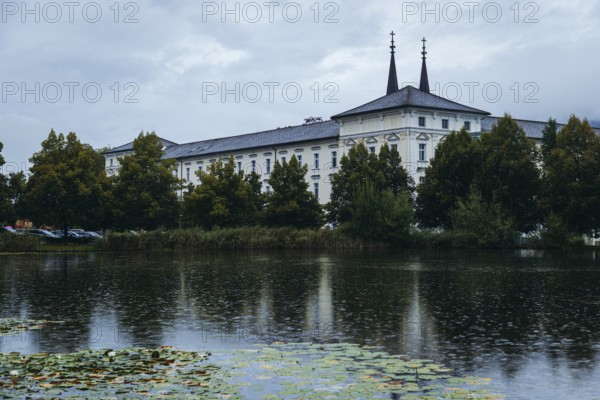 Admont Abbey is reflected in a pond surrounded by trees, Admont, Styria, Austria