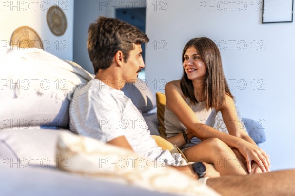 Happy couple enjoying time together, relaxing on a comfortable couch in their modern living room, engaged in conversation