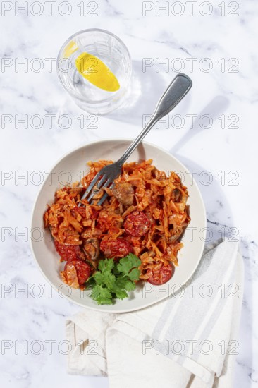 Bigos, Polish dish bigos, on a marble table, stewed meat with cabbage, chorizo sausages, mushrooms, homemade, without people
