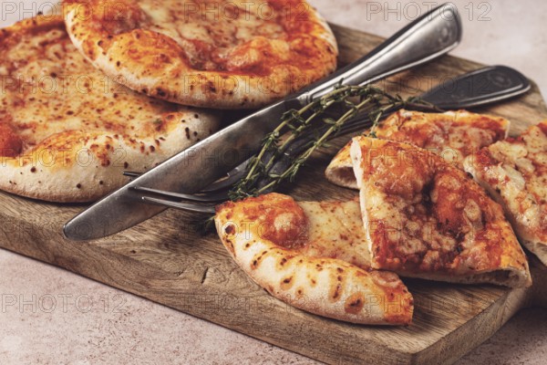 Four pizzetta Margaritas, on a cutting board, on a light gray surface, top view