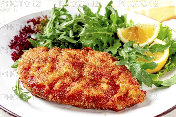 Milanese chicken, Crispy breaded chicken served, with fresh herbs, and lemon wedges