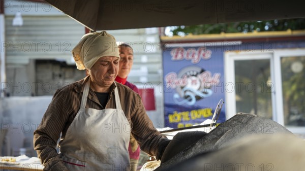A Turkish woman bakes traditional bread on a clay tandoor oven in a rural village, Hatay, Hatay, Türkiye