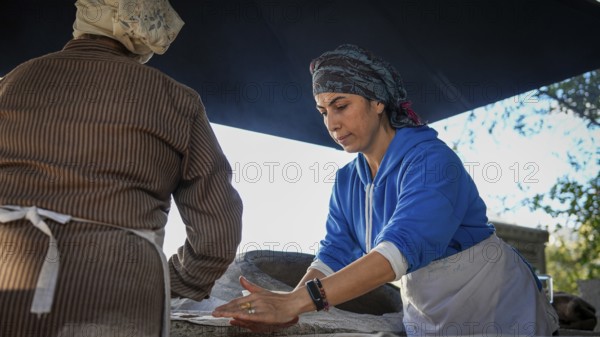 A Turkish woman bakes traditional bread on a clay tandoor oven in a rural village, Hatay, Hatay, Türkiye