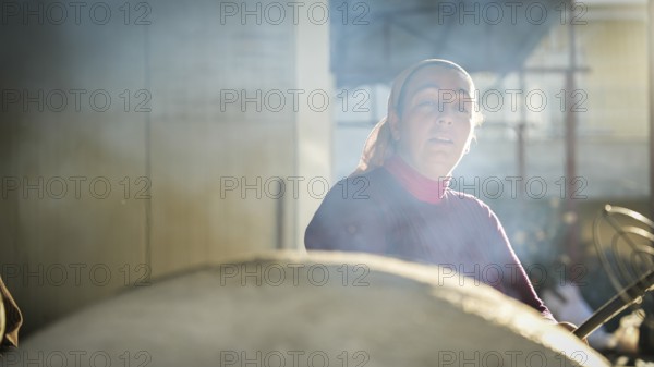 A Turkish woman bakes traditional bread on a clay tandoor oven in a rural village, Hatay, Hatay, Türkiye