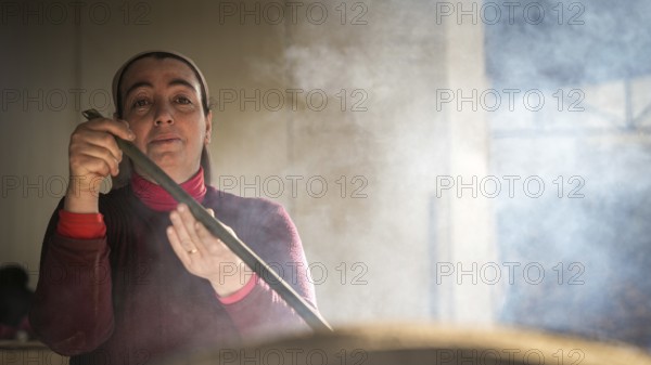 A Turkish woman bakes traditional bread on a clay tandoor oven in a rural village, Hatay, Hatay, Türkiye