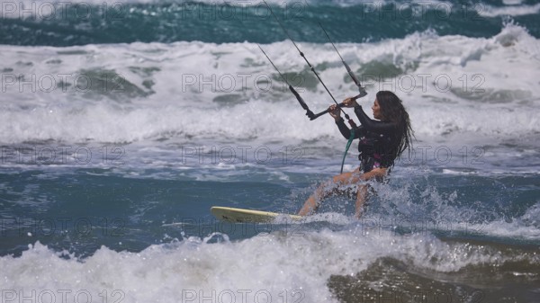 Woman kitesurfing energetically over waves in sunny sea environment, Prasonisi, beach, surf, windsurfer, kite surfer, waves, south coast, Rhodes, Dodecanese, Greek Islands, Greece