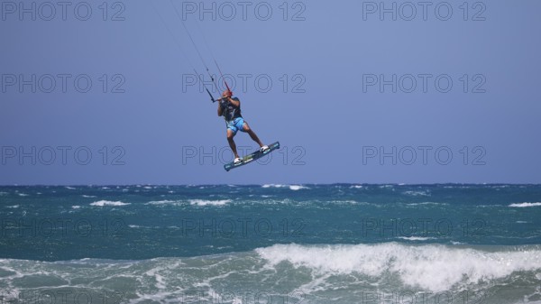 Kitesurfer jumping high over waves under a clear blue sky, Prasonisi, beach, surf, windsurfer, kite surfer, waves, south coast, Rhodes, Dodecanese, Greek Islands, Greece