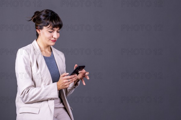 Professional woman with her phone on a gray background