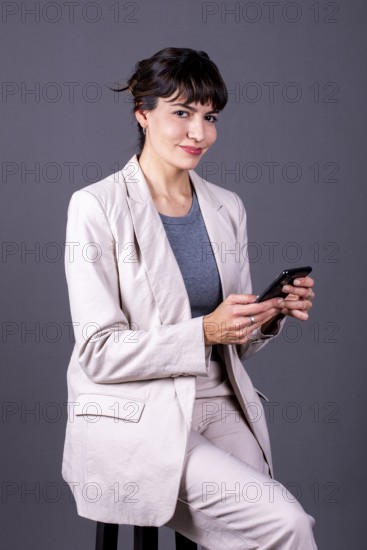 Elegant professional businesswoman holding her phone while looking at camera