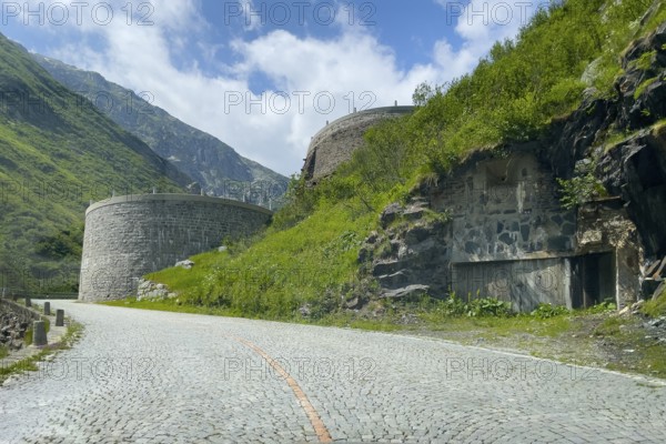 Part of southern ascent of south ramp of historic Gotthard pass road Tremola with cobblestones, in the background retaining walls for serpentines narrow hairpin bends on steep mountainside, Canton Ticino Ticino, Switzerland