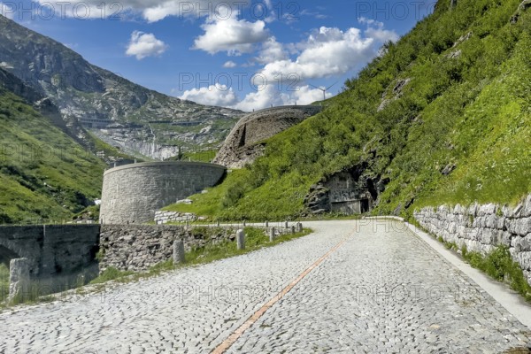 Part of southern ascent of south ramp of historic Gotthard pass road Tremola with cobblestones, in the background retaining walls for serpentines narrow hairpin bends on steep mountainside, Canton Ticino Ticino, Switzerland