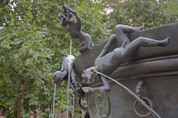 Detail with naked male figures hanging upside down on the edge of the water basin at the Faun Fountain by Heinrich Apel 1986, modern art, bronze sculptures, water jets, climbing, upside down, Devil's Fountain, Magdeburg, Saxony-Anhalt, Germany
