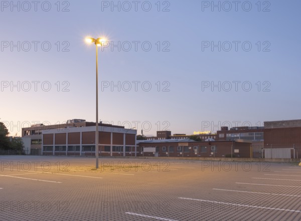 Taking a street lamp on an empty car park in front of an industrial building in the evening, Stöcken, Hanover, Lower Saxony, Germany