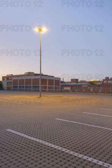 Taking a street lamp on an empty car park in front of an industrial building in the evening, Stöcken, Hanover, Lower Saxony, Germany