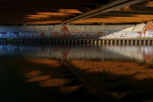View across the Mittelland Canal to the underside and the graffiti-painted abutment of a bridge on the B6, Hanover, Lower Saxony, Germany