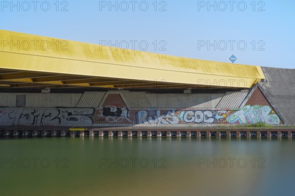 View across the Mittelland Canal to the underside and the graffiti-painted abutment of a bridge on the B6, Hanover, Lower Saxony, Germany