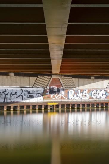 View across the Mittelland Canal to the underside and the graffiti-painted abutment of a bridge on the B6, Hanover, Lower Saxony, Germany