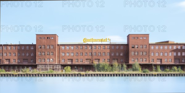 View across the Mittelland Canal to an industrial building with trees growing in front of it, long exposure, Garbsen, Hanover, Lower Saxony, Germany