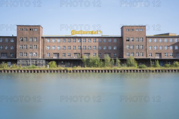 View across the Mittelland Canal to an industrial building with trees growing in front of it, long exposure, Garbsen, Hanover, Lower Saxony, Germany