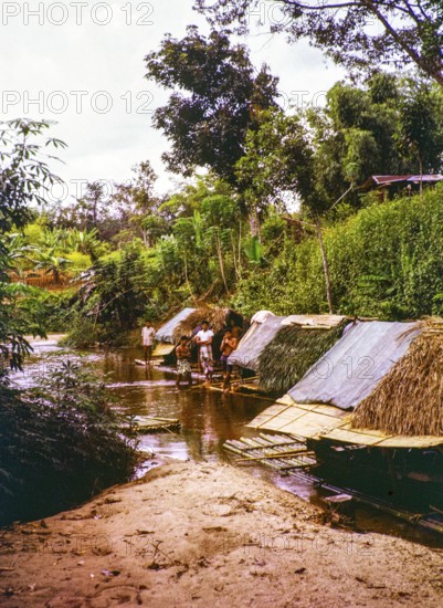 People living in homes on river house rafts, Sungai Perdak, Pahanh, Bentong district, Malaya, Malaysia, south east Asia, 1963 captioned as 'Sungai Peredak'