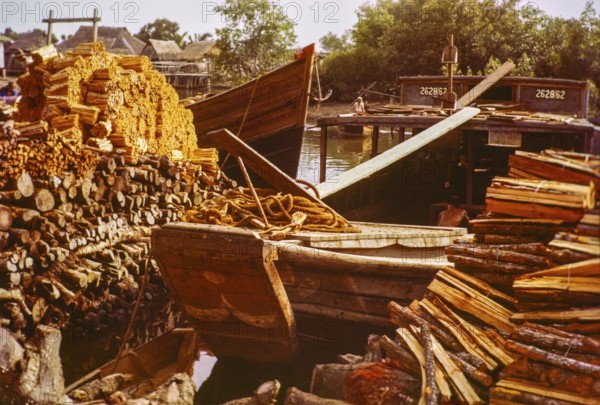 Loading wood timber products onto barge boat in timber yard, Johor Bahru, Johor, Malaya, Malaysia, south east Asia 1963