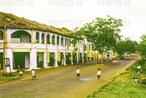 Row of Chinese shophouses businesses in building, unspecified location in Malaya, Malaysia, south east Asia 1963 - closest business is Tuck Seng dentist and watch maker