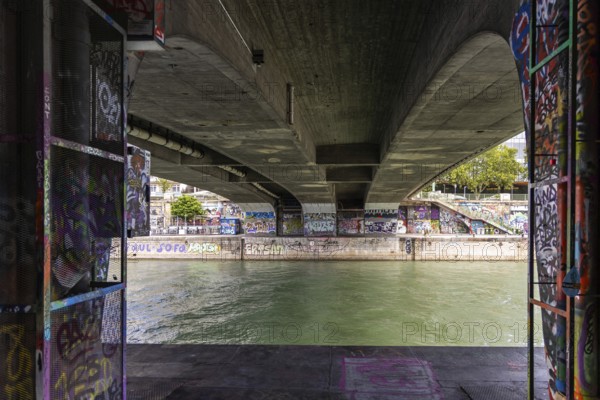 View under a bridge with graffiti on the walls over a river, Am Donaukanal Innere Stadt Vienna Austria