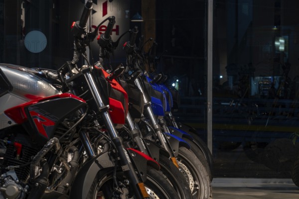 A row of motorcycles in varying colors displayed indoors at a showroom-Dhaka, Bangladesh