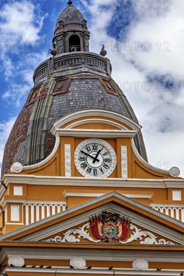 Architecturally richly decorated tower with clock and coat of arms under a cloudy sky, The Presidential Palace of La Paz in Bolivia