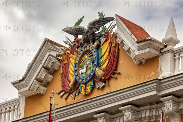 Detailed coat of arms with eagle on a historic building under a cloudy sky, The Presidential Palace of La Paz in Bolivia