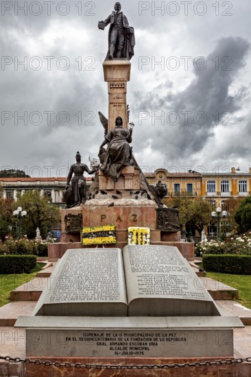 A monument with an imposing statue surrounded by a dramatic sky and historic buildings, monument in the streets of La Paz in Bolivia