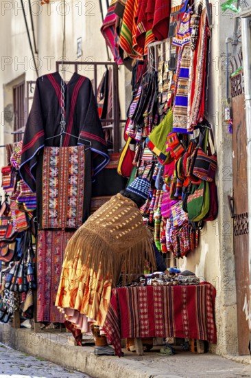 A shop in a narrow street offers colourful, handmade textiles and clothing with traditional patterns, souvenir shops in La Paz Bolivia
