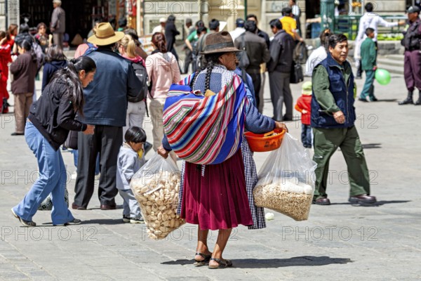 A woman at a market with large bags and a traditional hat, Traditionally dressed woman in the streets of La Paz Bolivia
