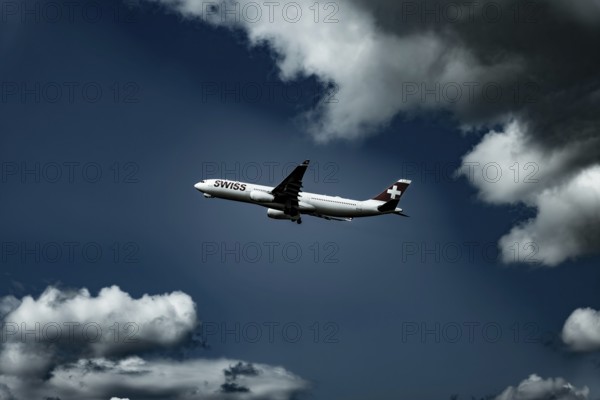 Swiss Airlines Passenger Airplane Flying Against Blue Sky and Clouds in a Sunny Summer Day From the Airport in Kloten, Zurich, Switzerland
