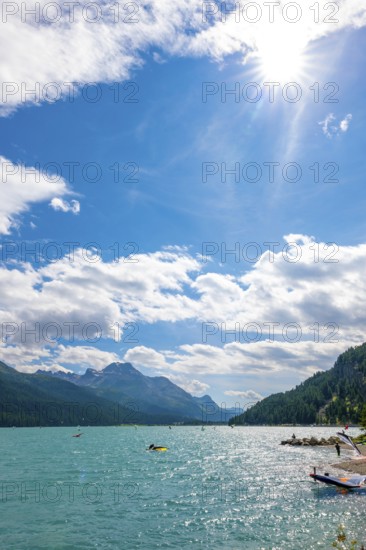 Windsurfing and Wingsurfing on Alpine Lake Silvaplana in a Sunny Summer Day with Mountain View in the Swiss Alps and Sunbeam in Silvaplana, Maloja, Grisons, Switzerland