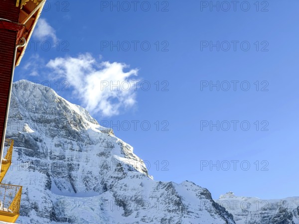 Hotel and Snowcapped Mountain Peak Mönch at 4107 Meter High in the Swiss Alps in a Sunny Winter Day with Blue Sky in Grindelwald, Bern Canton, Switzerland