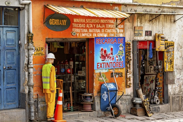 A small shop with an orange façade and various tools in an urban street scene, A small DIY store in the streets of La Paz in Bolivia