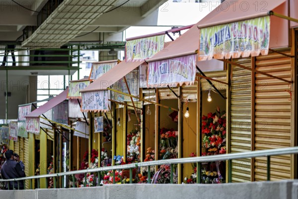 Quiet row of flower shops with creatively presented, colourful flowers, small shops and restaurants in the market halls of La Paz in Bolivia