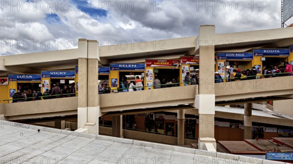 Long view of the upper floor of a market with colourful stalls and many customers, Small shops and restaurants in the market halls of La Paz in Bolivia