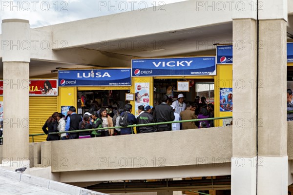 Crowd in front of stalls with blue signs in a modern market complex, Small shops and restaurants in the market halls of La Paz in Bolivia