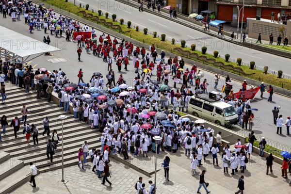 Large gathering of people with umbrellas on a city street, flanked by buildings, A demonstration in the streets of La Paz, Bolivia