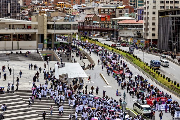 Crowds gather on stairs and streets, next to urban buildings with traffic, A demonstration in the streets of La Paz, Bolivia