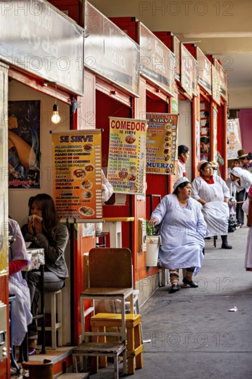 Lively market with food stalls and seated people in colourful, lively surroundings, Small shops and restaurants in the market halls of La Paz in Bolivia