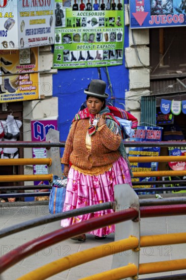 A woman in traditional dress walks through a colourful market street in Bolivia, A traditional woman in the streets of La Paz in Bolivia