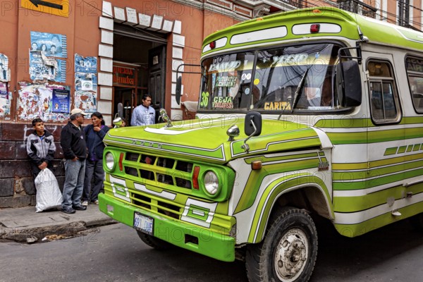 Green retro bus in front of a municipal building with people on the pavement, The colourful buses of La Paz in Bolivia